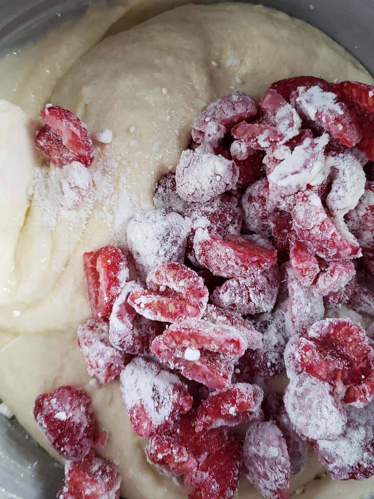 Raspberries coated in flour on top of cupcake batter.