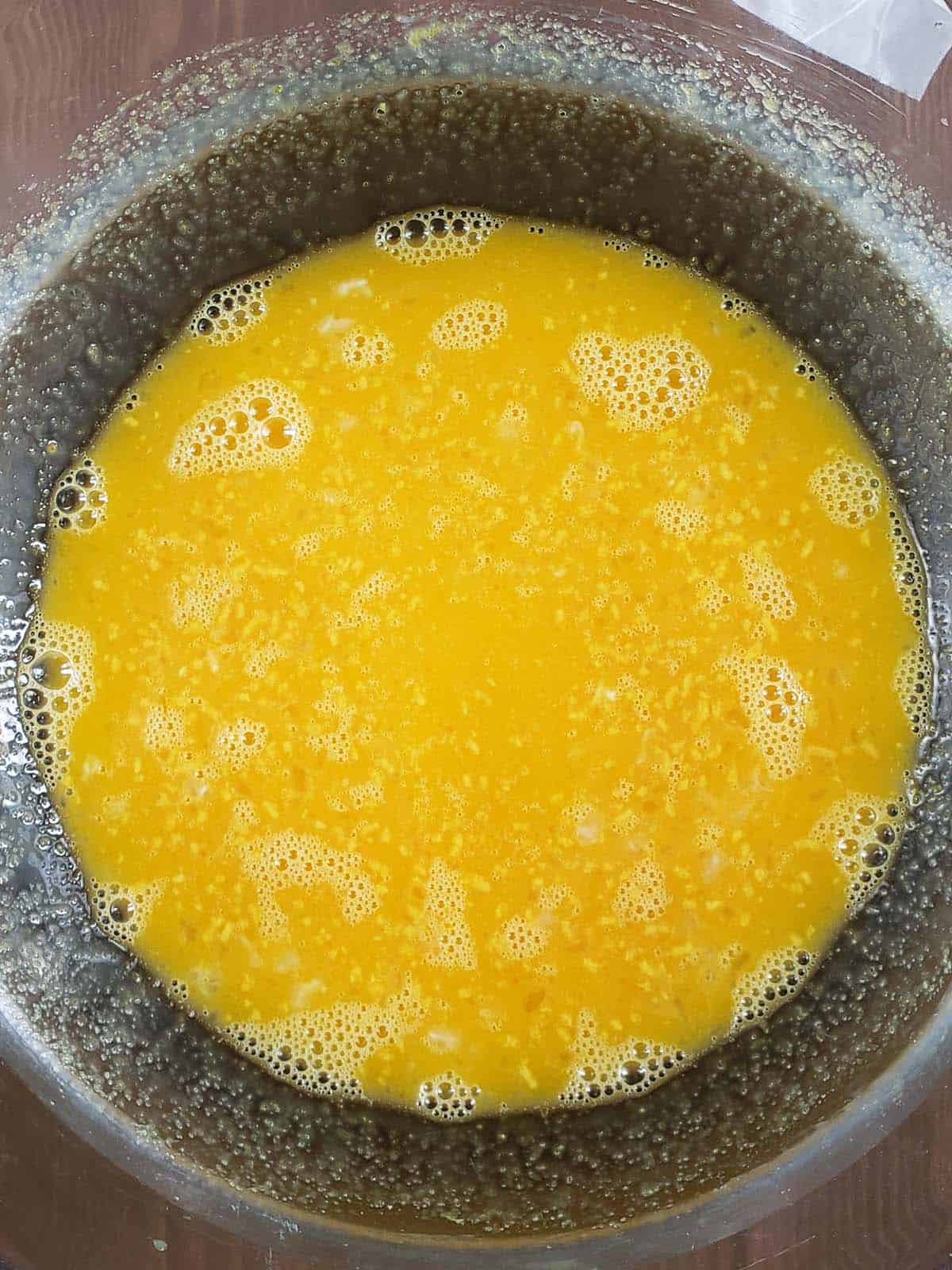 Egg yolks and sugar whisked together in a glass bowl.