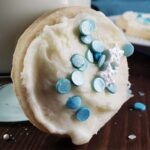 Iced sugar cookie leaning against a glass of milk.