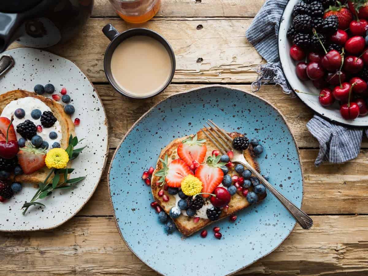 French toast on a light blue plated topped with berries.