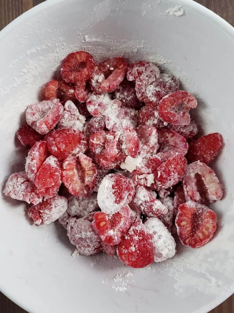 Raspberries coated in flour in a white bowl.