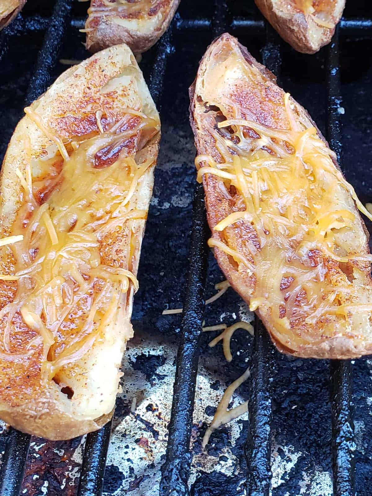 Smoked potato skins with melted cheese on a grill.