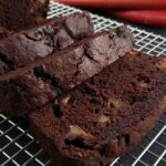 Sliced rhubarb chocolate cake on a wire cooling rack.