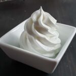 Lemon swiss meringue piped into a square white container.