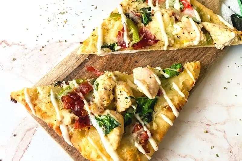 Chicken bacon ranch flatbread on a white surface.