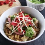 Pesto, chicken, and quinoa in a white bowl.