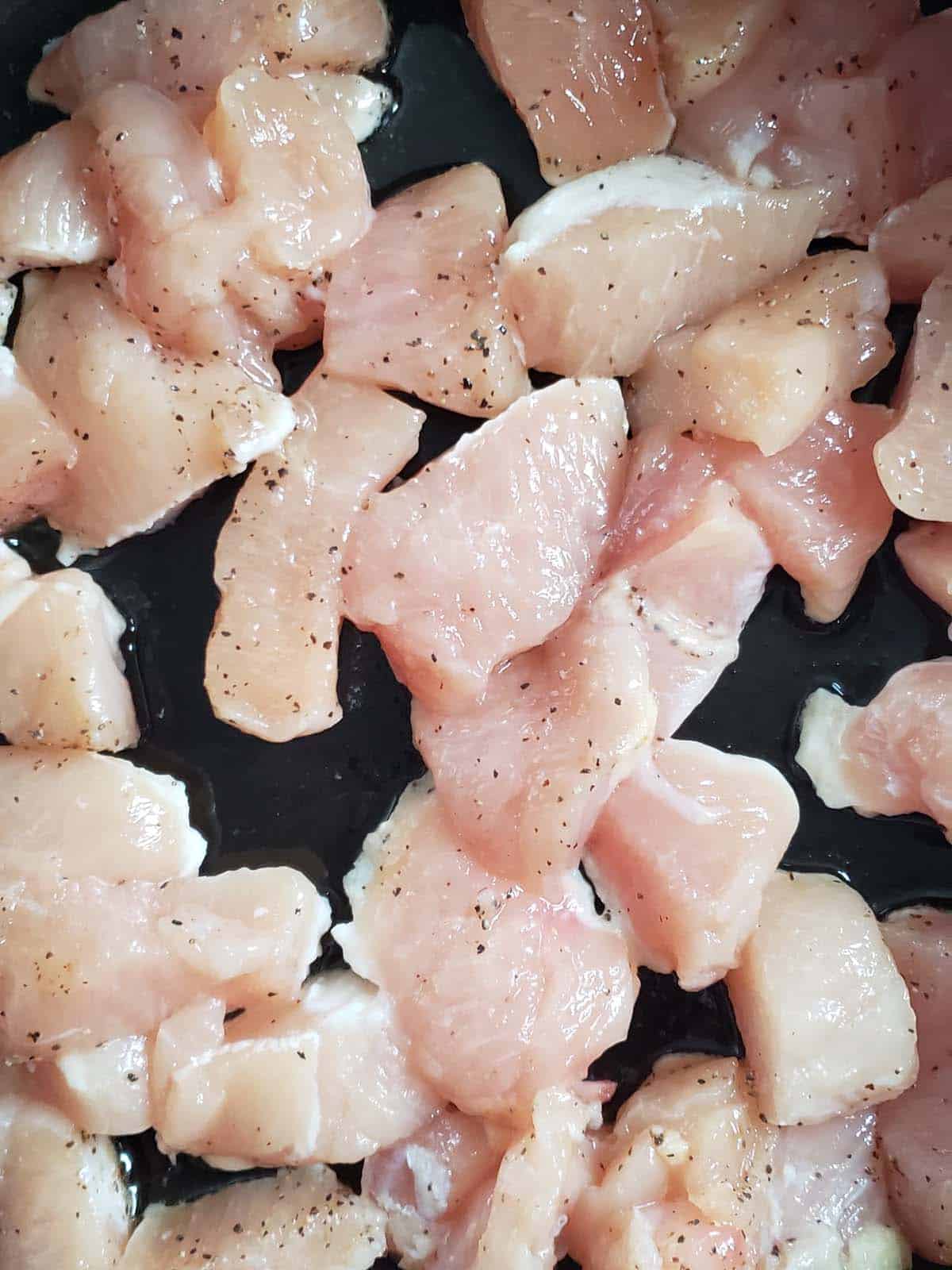 Raw chicken breast cut into small pieces.