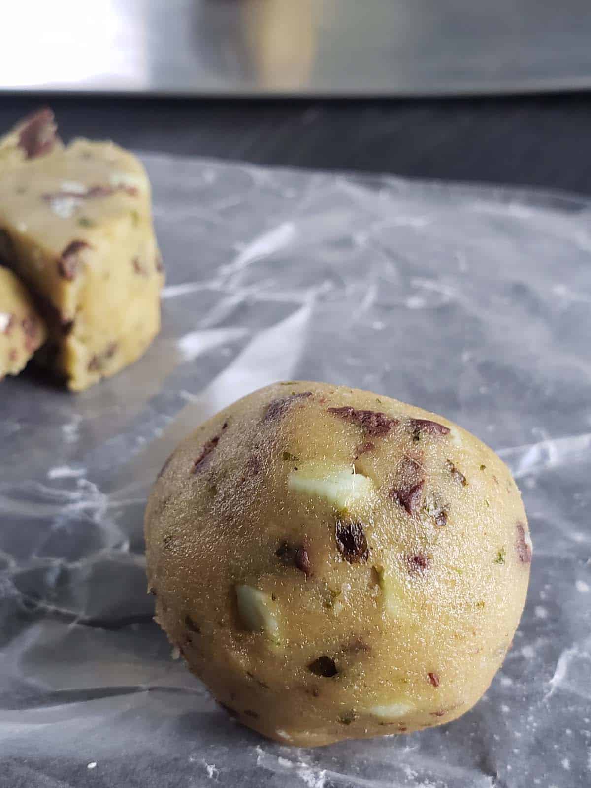 Mint chocolate chip cookie dough rolled into a ball on wax paper.