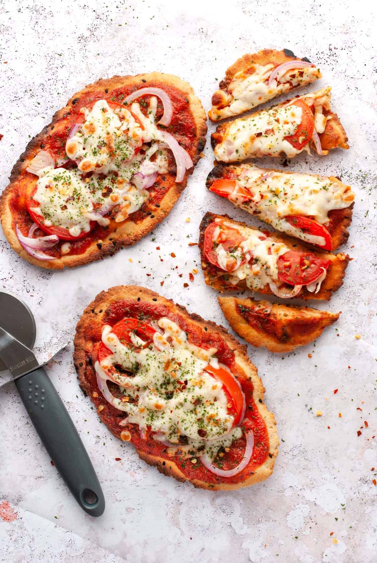 Top down view of three naan flatbread pizzas.