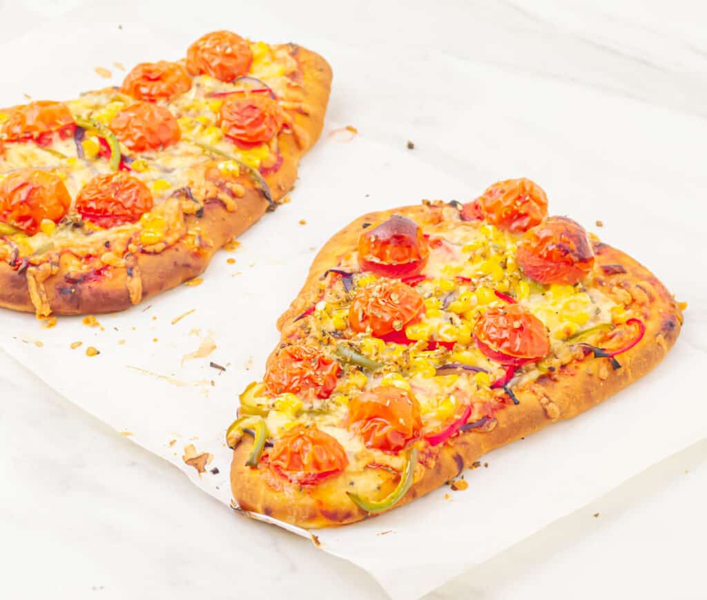 Vegetable flatbread pizza on a white surface.