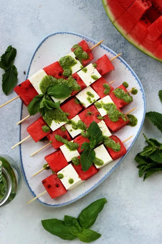 Watermelon and feta skewers on a white platter.