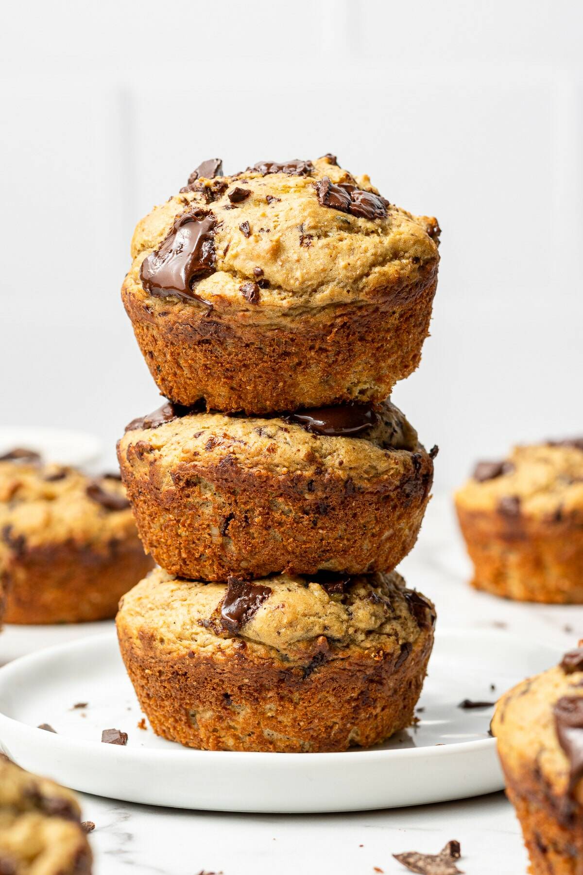 Stack of three chocolate banana muffins on a white plate.