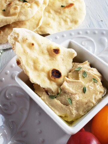 Piece of flatbread dipped in hummus.