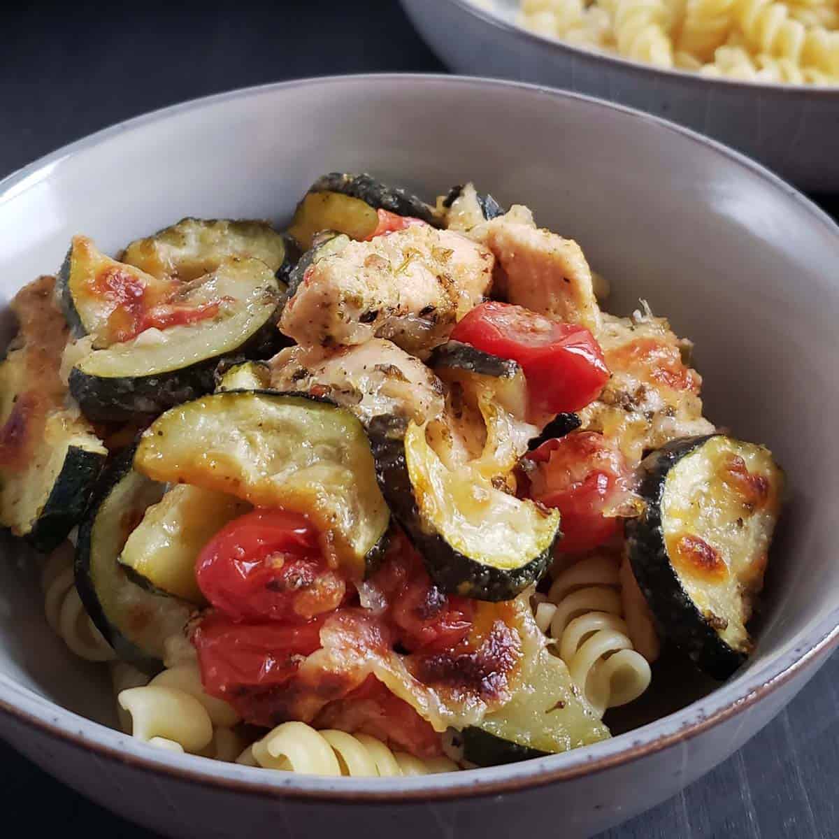 Zucchini, chicken, and tomatoes with pasta in a bowl.