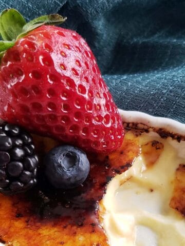 Close up of creme brulee topped with mixed berries.