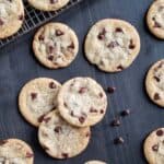 Chocolate chip cookies scattered on a black wood surface.