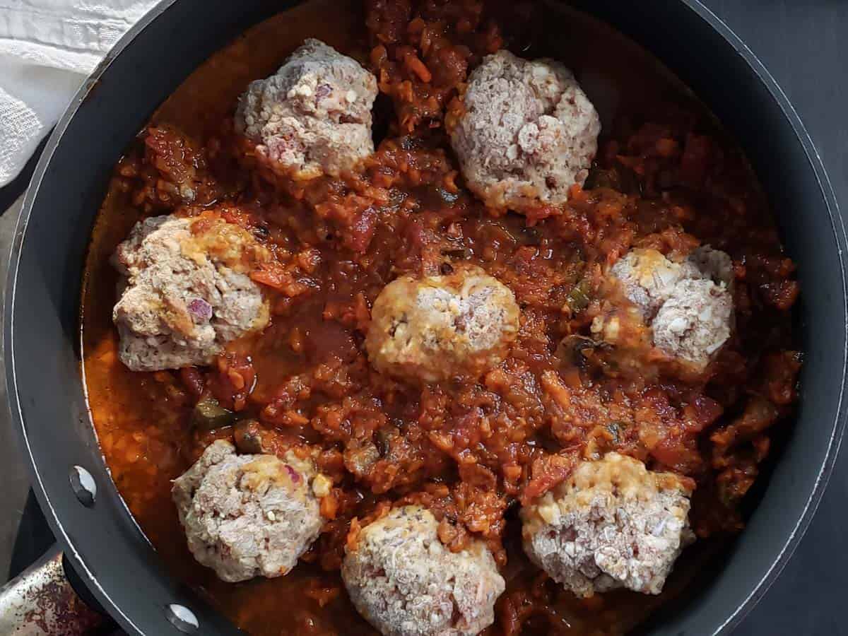 Meatballs and pasta sauce in a sauce pan.