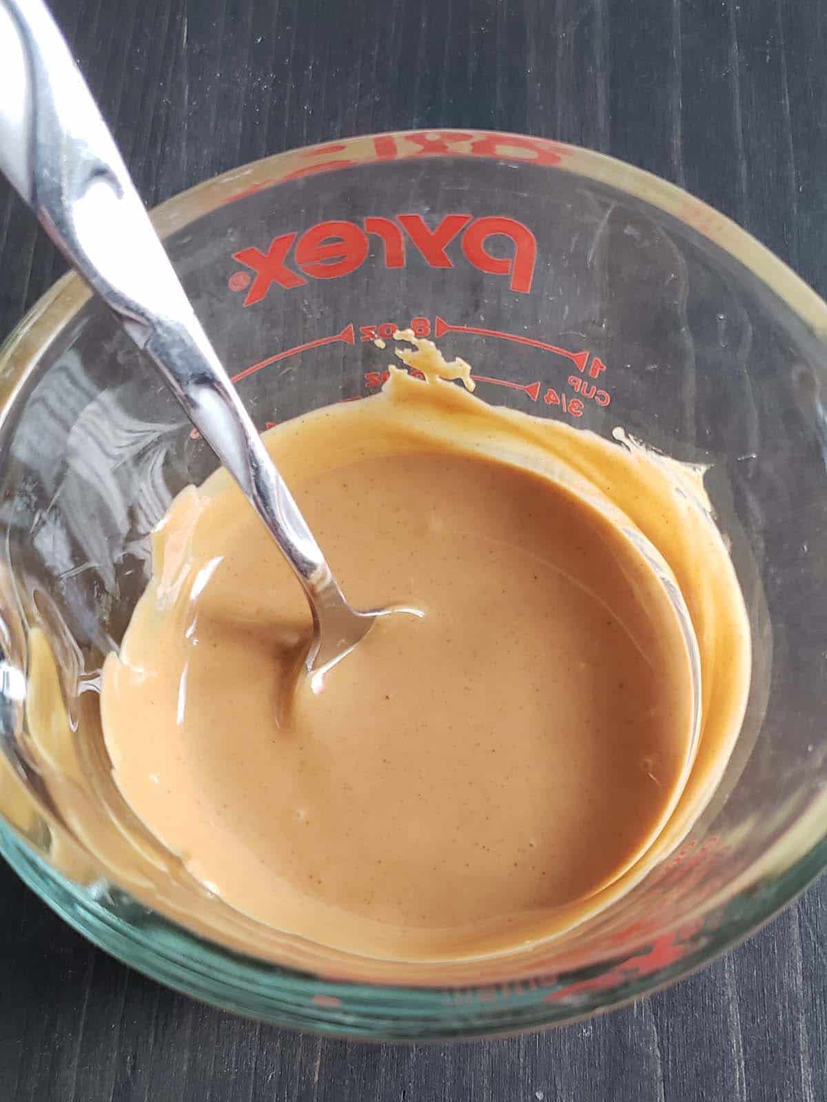 Melted peanut butter in a glass measuring cup.