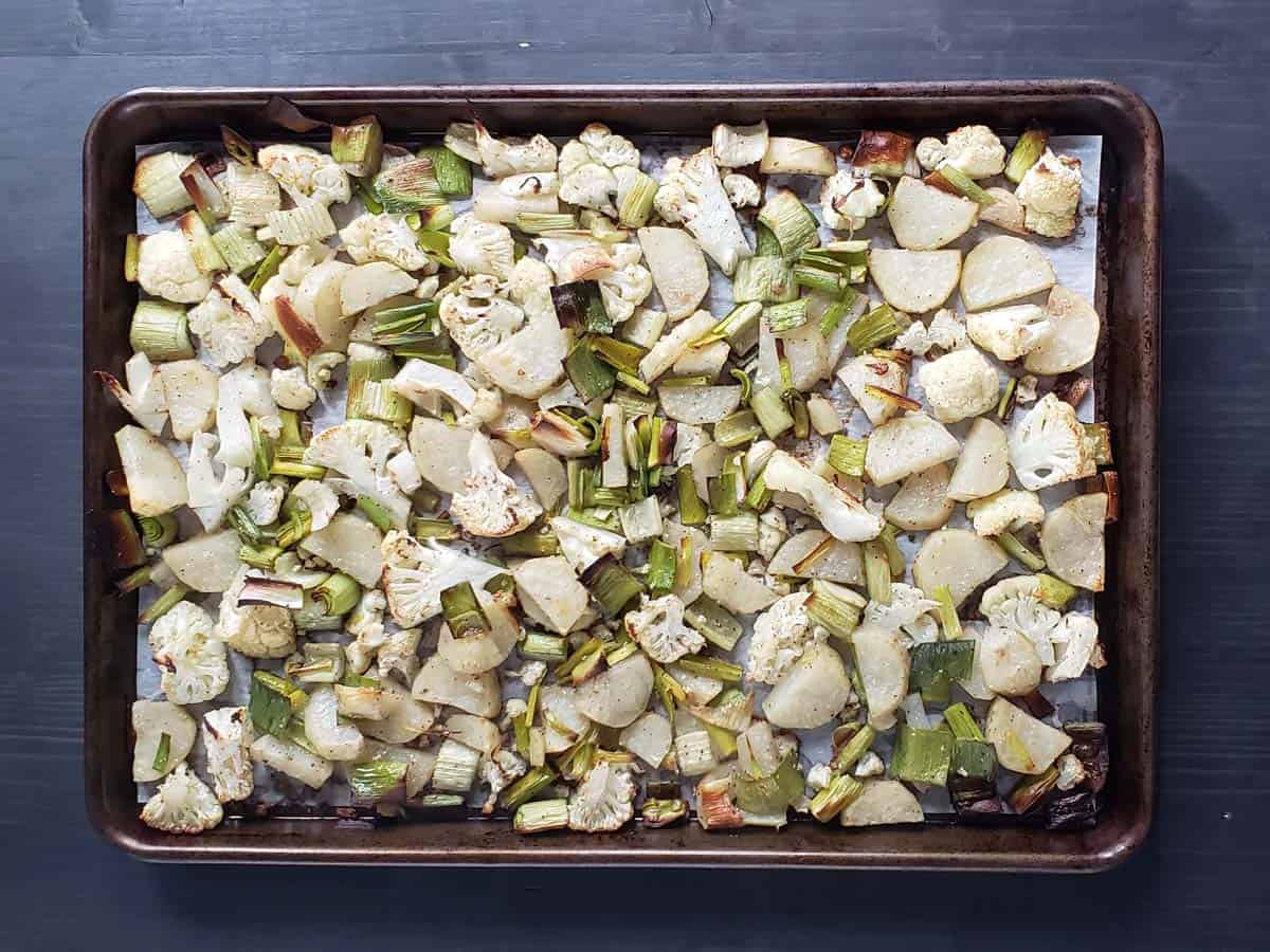 Roasted cauliflower, leeks, and potatoes on a baking sheet.