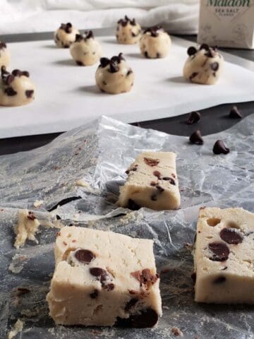 Chocolate chip cookie dough cut into squares on wax paper.