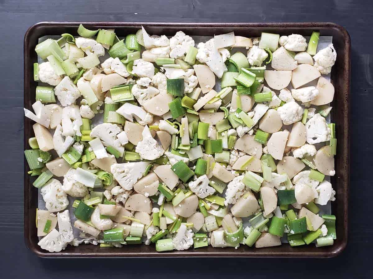 Chopped cauliflower, leeks, and potatoes on a baking sheet.