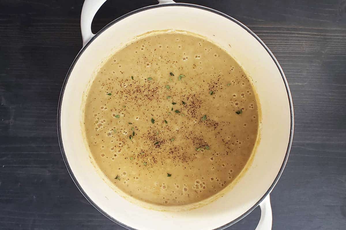 Pureed roasted potato cauliflower leek soup pureed in a white Dutch oven.