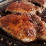 Three pork chops on a baking sheet.