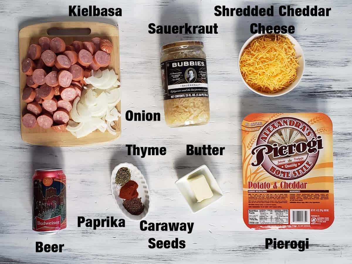 Kielbasa, pierogi, and sauerkraut ingredients on a white surface.
