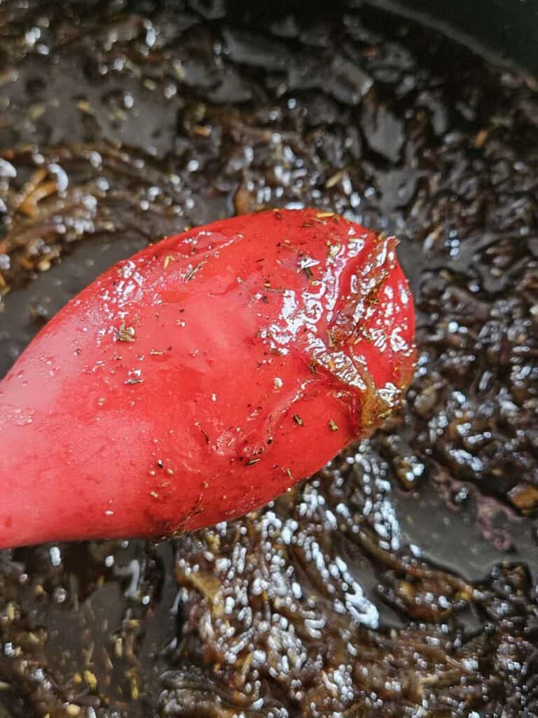 Maple onion jam coating the back of a red spoon.