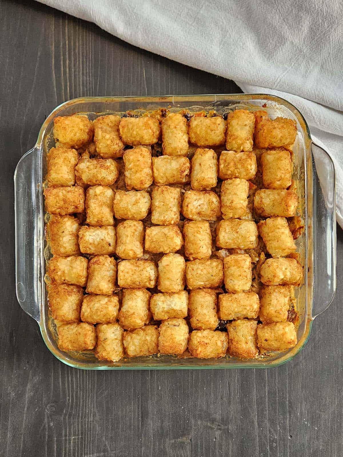 Pork casserole topped with tater tots in a glass casserole dish.