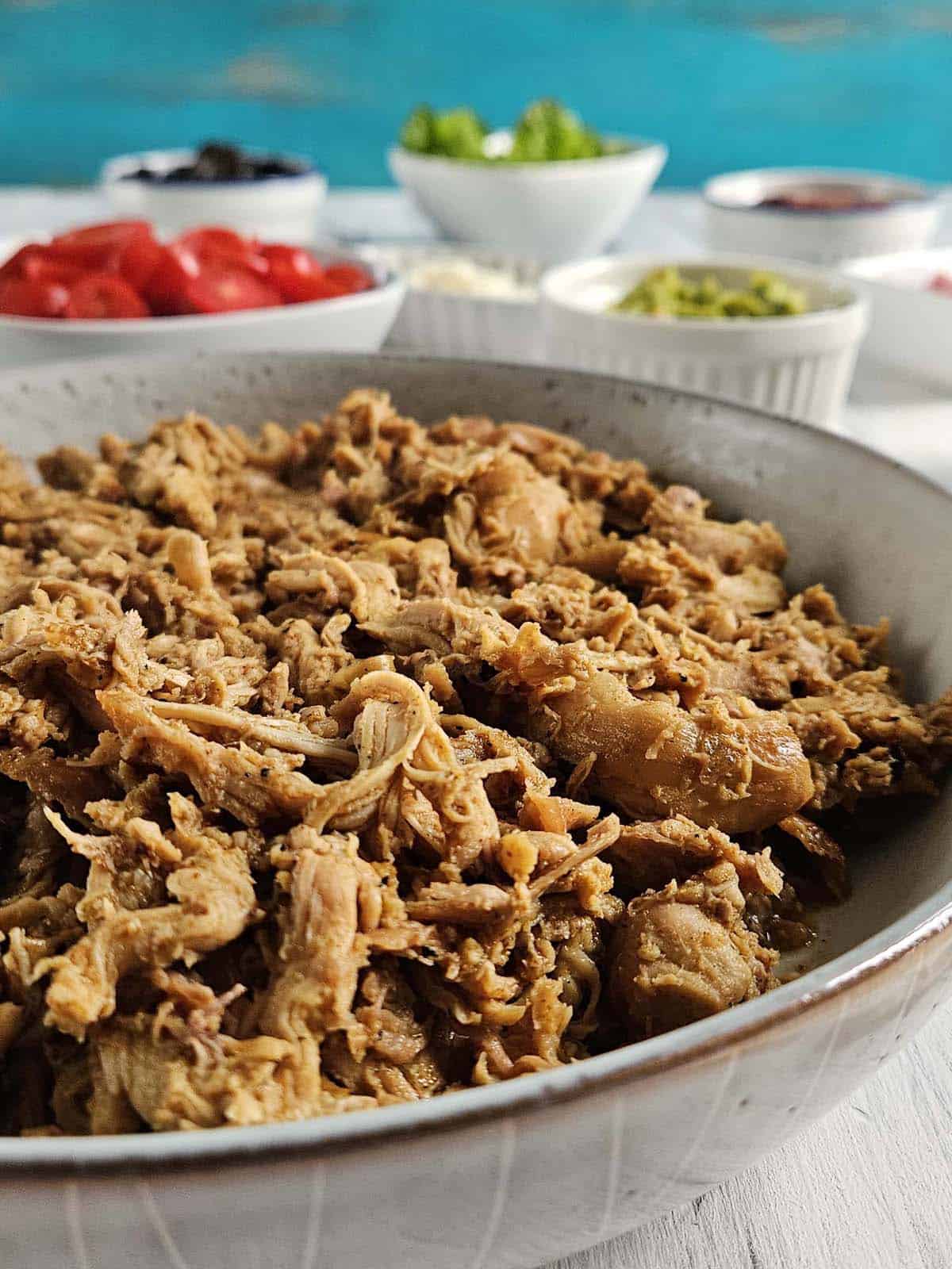 Close up of pulled pork in a ceramic bowl.