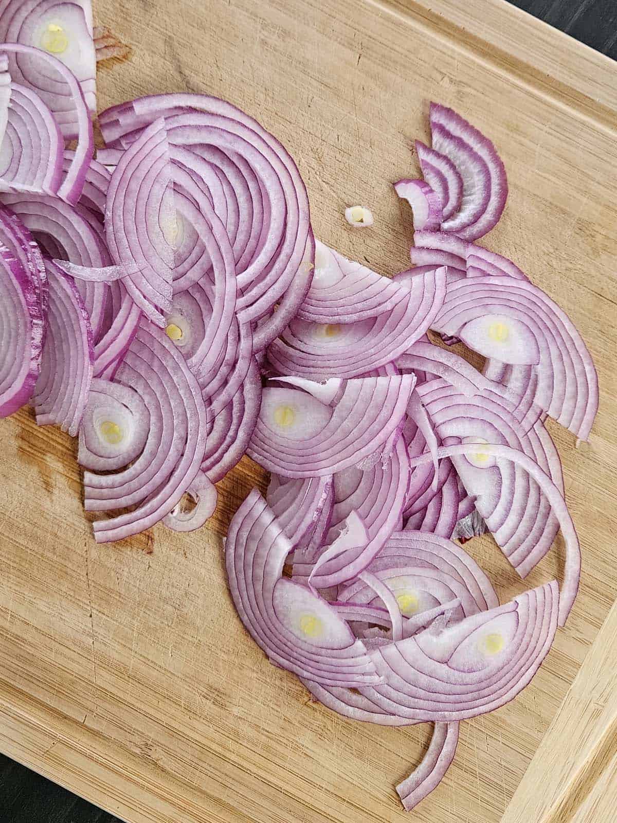 Slice red onions on a cutting board.