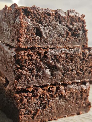 A stack of three brownies on parchment paper.