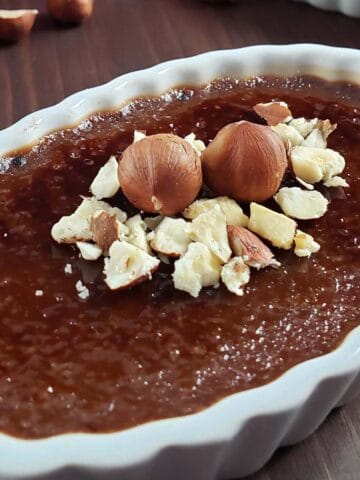 Nutella creme brulee in a white ramekin topped with chopped hazelnuts.