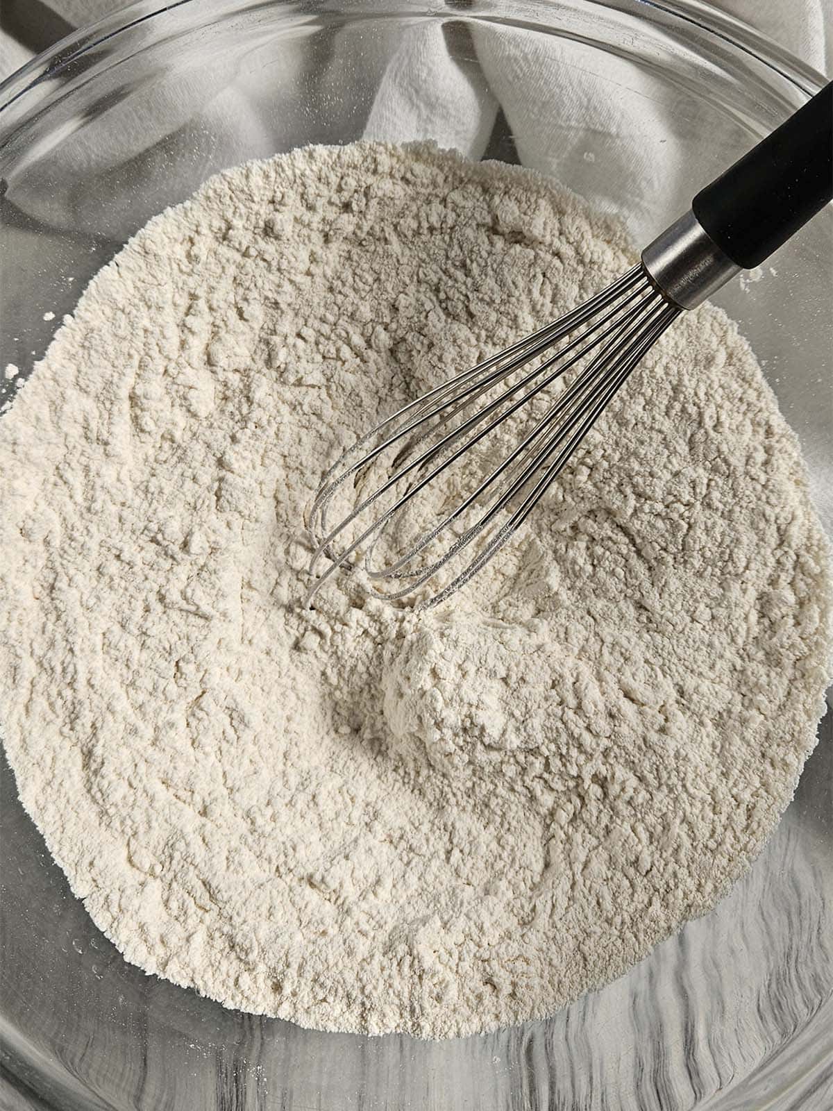 Flour and a whisk in a glass bowl.