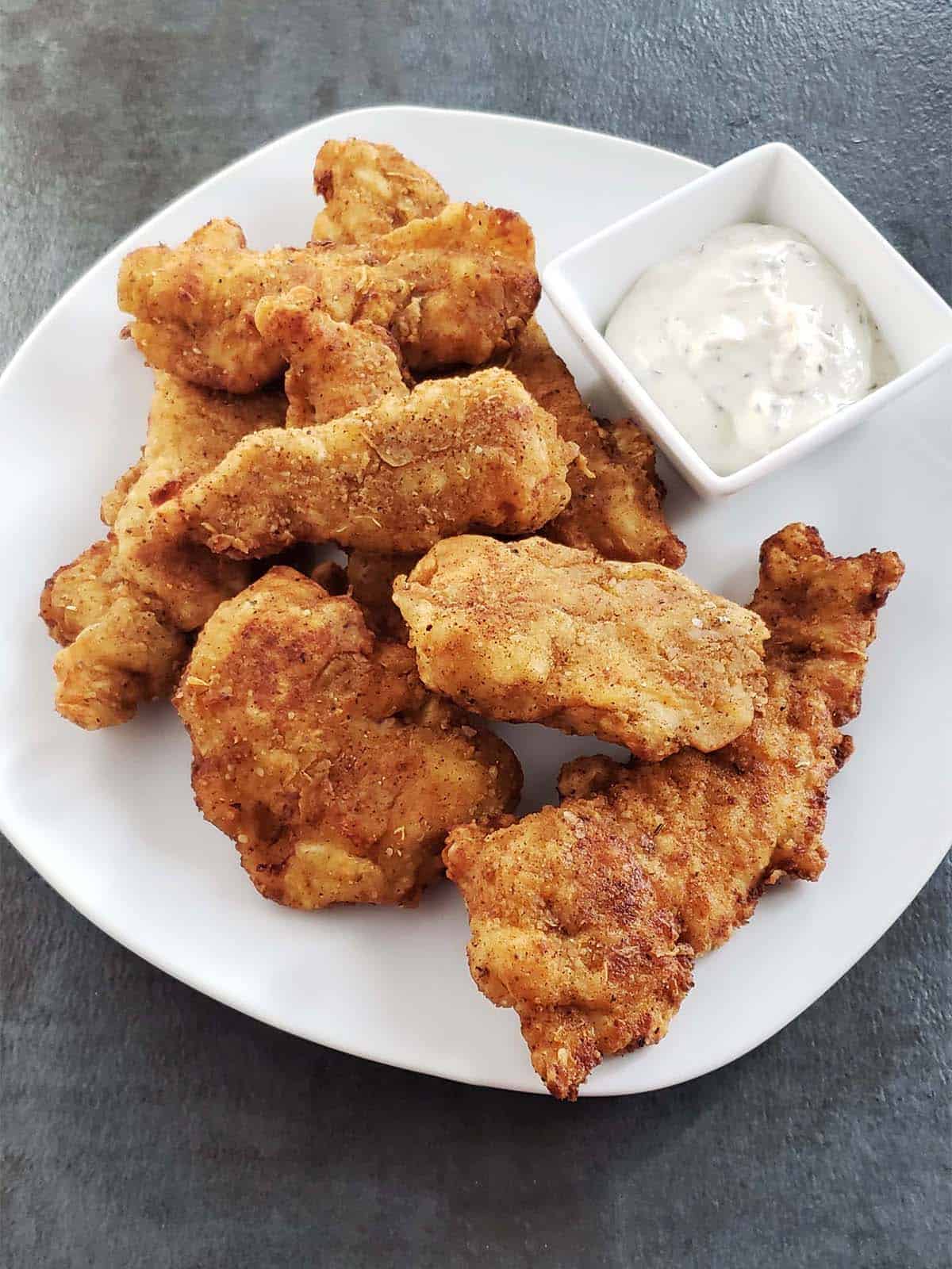 Sourdough chicken strips on a white plate.