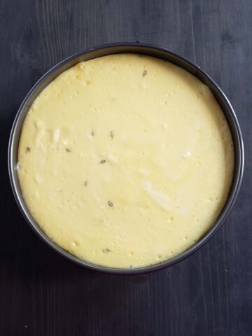 Baked cheesecake cooling on a dark wood surface.