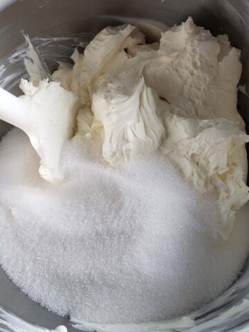 Blended cream cheese and sugar in a metal bowl.