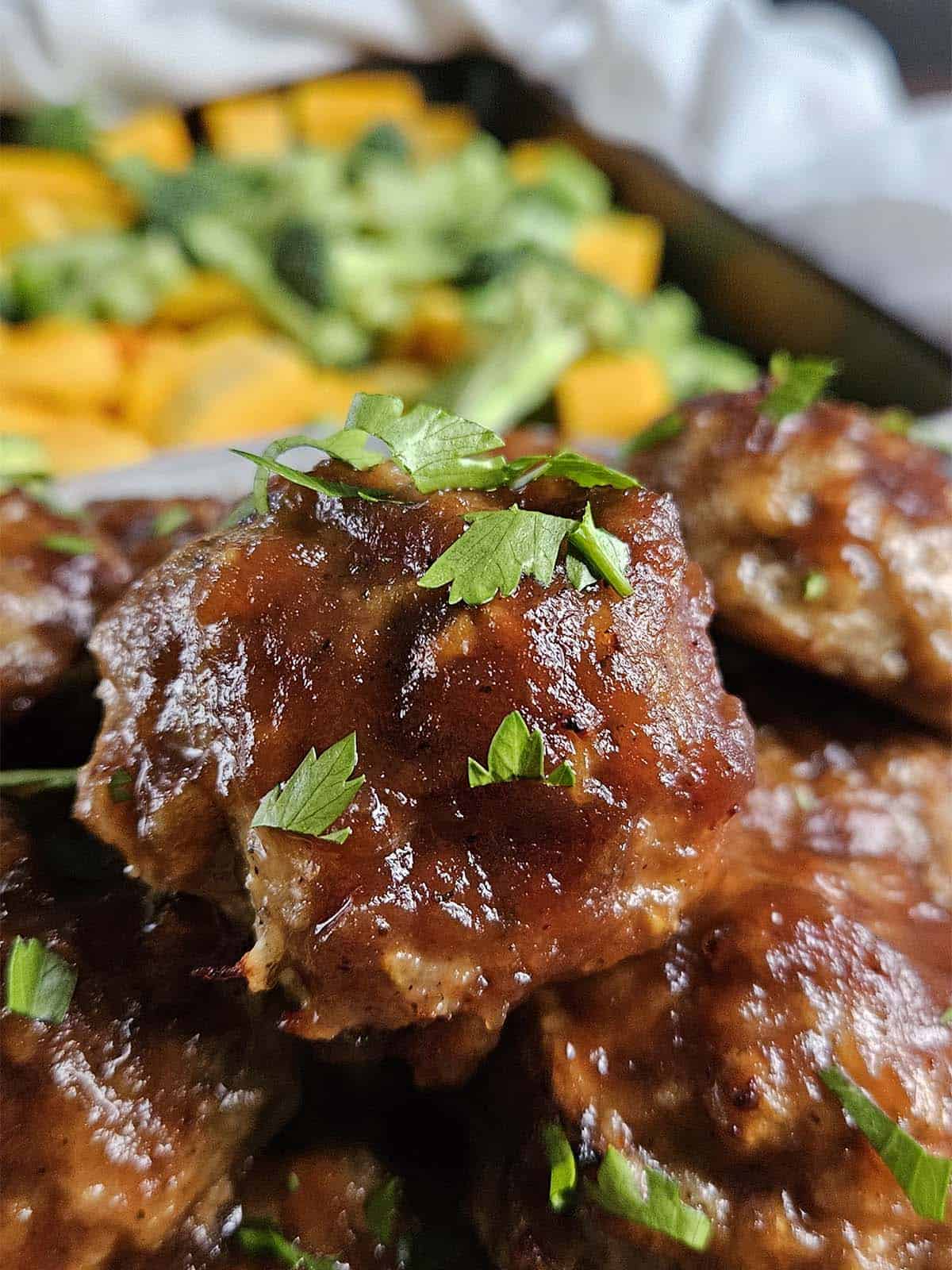 Meatball covered in sauce and chopped parsley.