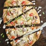 Greek pizza cut into triangles on a dark baking sheet.