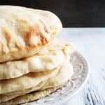 Stack of five pita bread on a white plate.