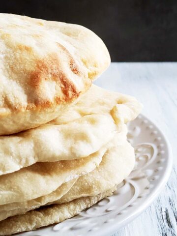 Stack of five pita bread on a white plate.