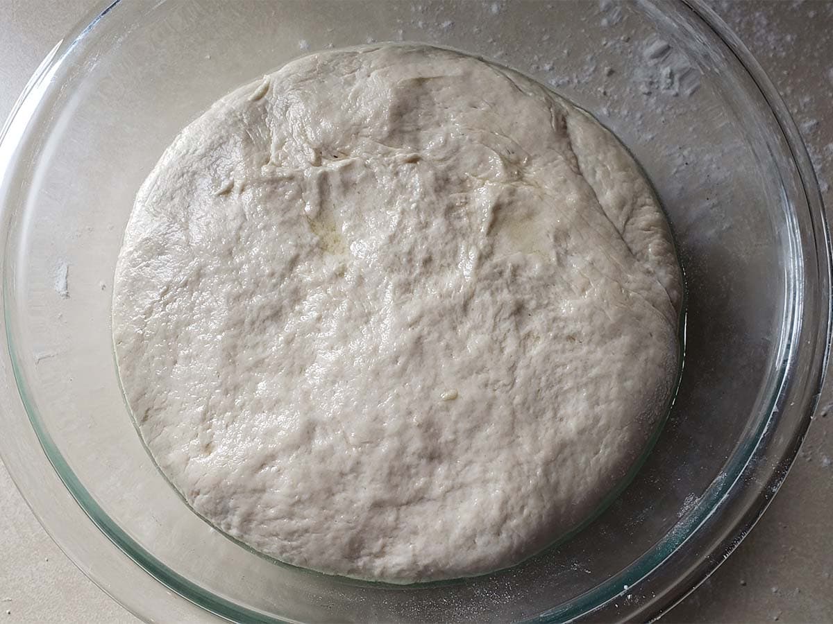 Pita dough rising in a glass bowl.