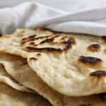 Stack of sourdough flatbread wrapped in a white towel.