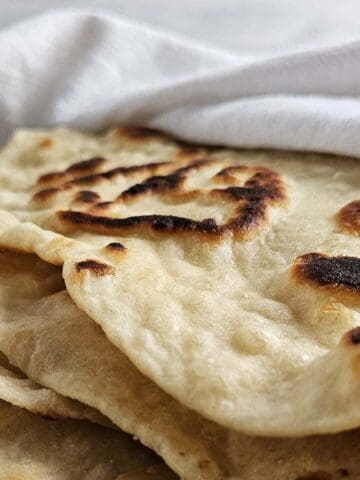 Stack of sourdough flatbread wrapped in a white towel.