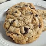 Three chocolate chip cookies on a white plate.