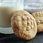 Sourdough peanut butter cookie propped up on a glass of milk.