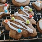 Gingerbread cookie tree topped with icing and sprinkles on a wire rack.