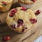 Orange Cranberry muffin on a wooden cutting board.