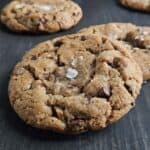 Two sourdough turtle cookies on a dark wood surface.